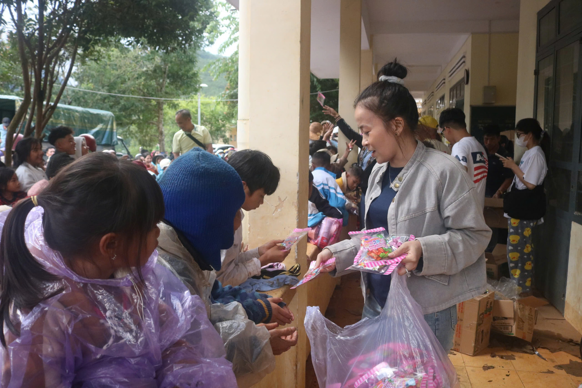 Volunteer giving sweets to children along the school corridor