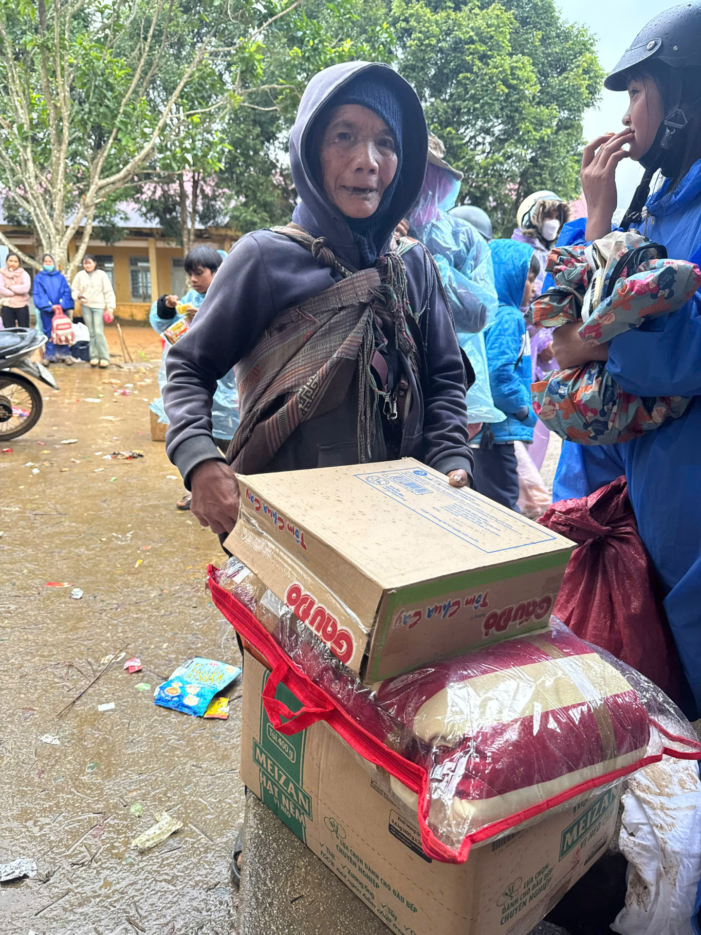 An elderly villager carrying a box of food supplies