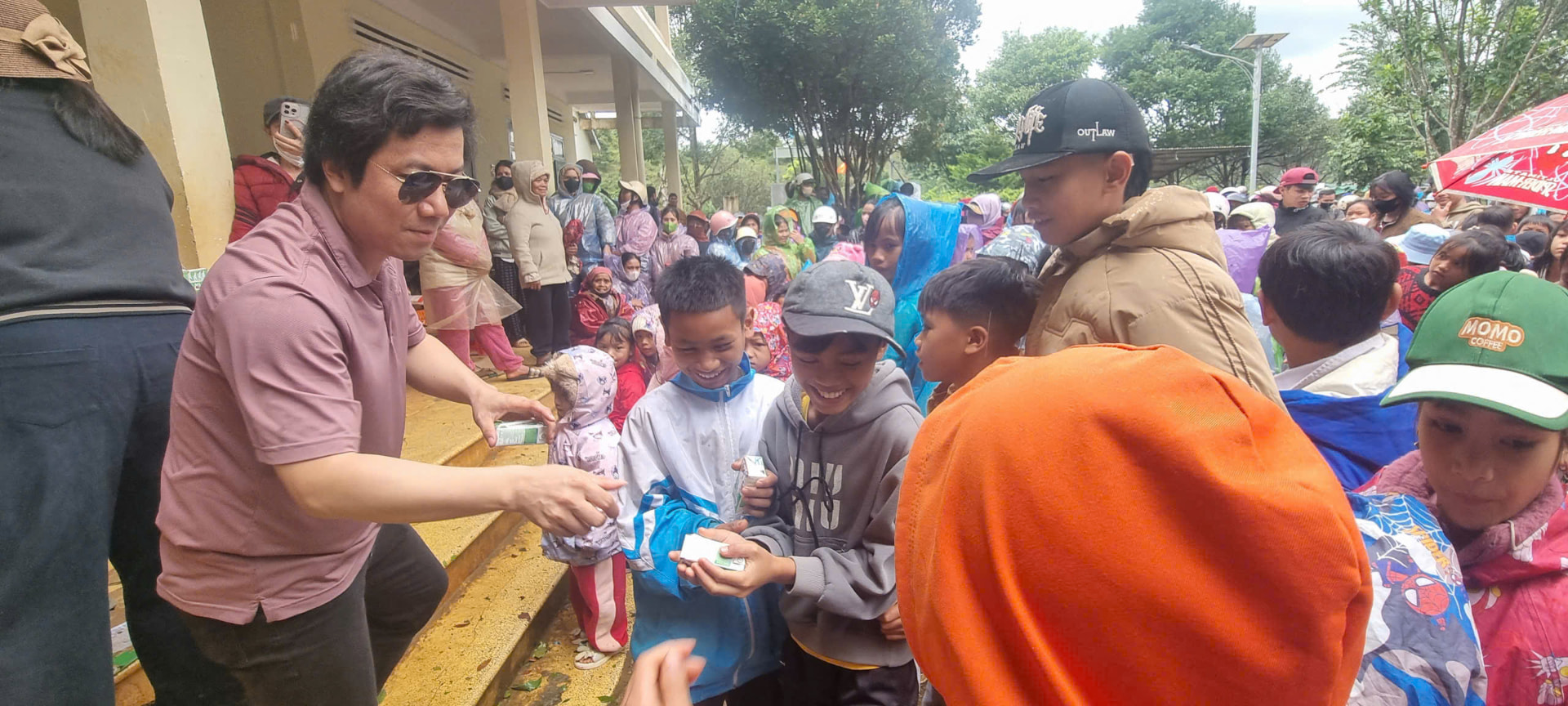 Volunteer handing milk cartons to children in the rain